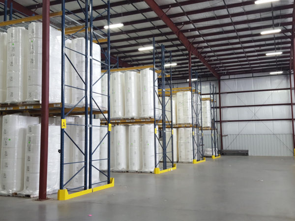 Pallet rack with blue uprights and yellow beams filled with product protected by row end guards.