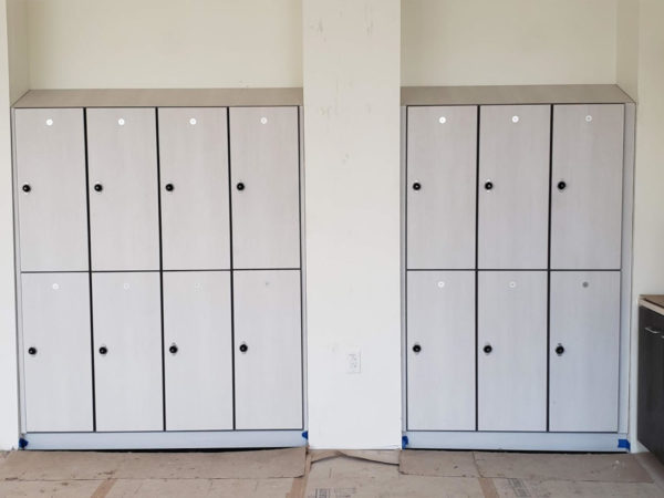 Two-tier plastic laminate lockers in a hallway, with a light gray finish.