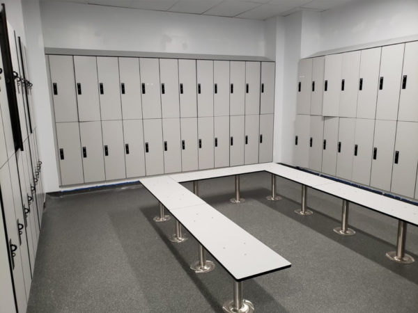 Two-tier plastic laminate lockers and benches in a locker room, with a light gray finish.