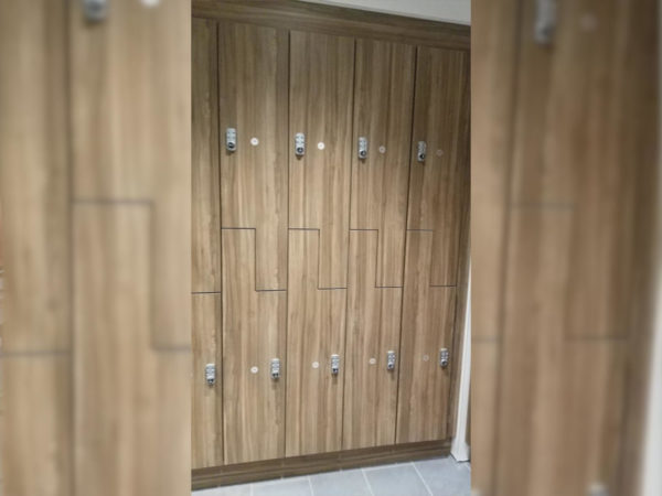 Two-tier phenolic lockers in a hallway, with a wood style finish.