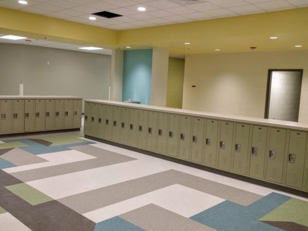 Single-tier half-height metal lockers in a hallway, with a tan finish.