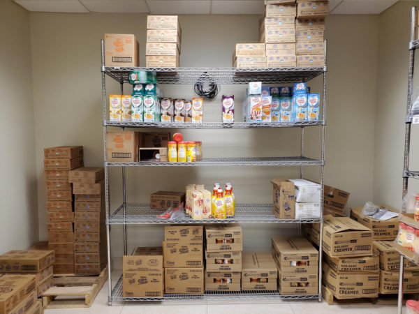 Wire shelving filled with break room items in a storage room.