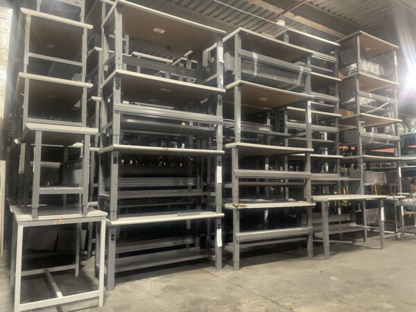 Multiple used workbenches stacked up, assorted sizes and conditions