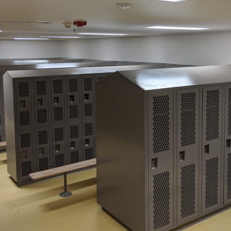 Single-tier and two-tier Heavy Duty Ventilated Athletic Lockers in a locker room, with a dark gray finish.