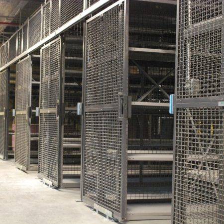 A wire partition cage with metal shelves inside, both gray in color.